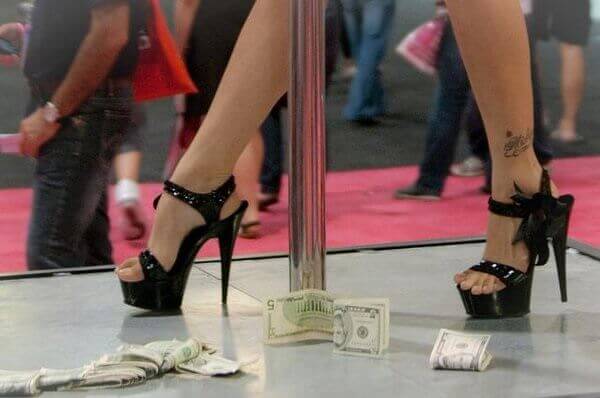 A sex worker walks on stage with money.
