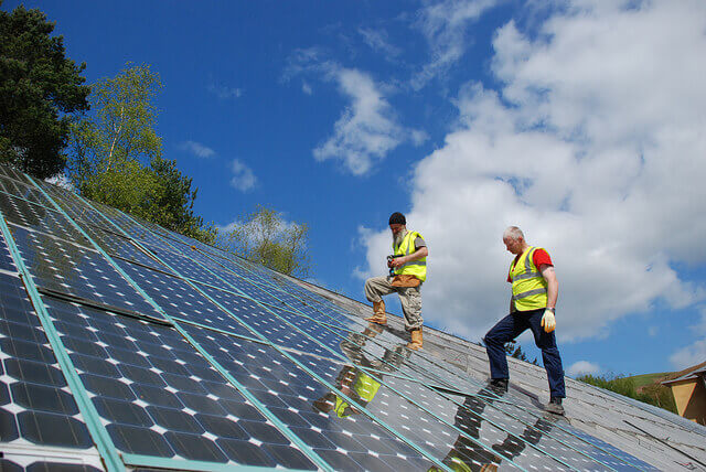 Workers walks across slanted solar panels. 