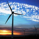 A wind turbine appears over a sunset horizon.
