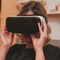 A woman sits wearing a VR headset.