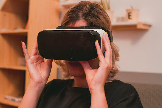 A woman sits wearing a VR headset.