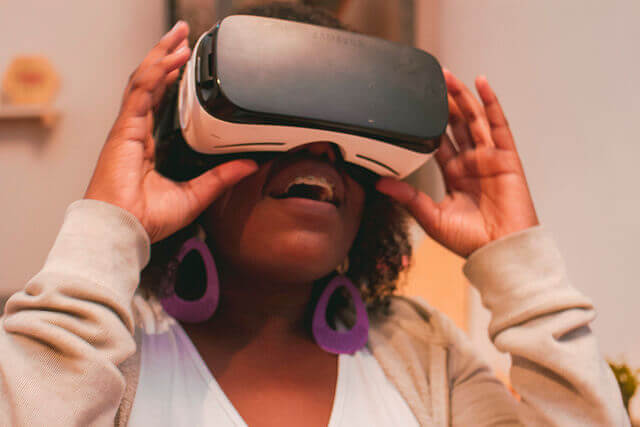 A young woman smiles while wearing a VR headset.