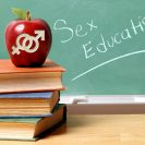 An apple with male and female symbols carved into it appears in front of a chalkboard that says "Sex Education."