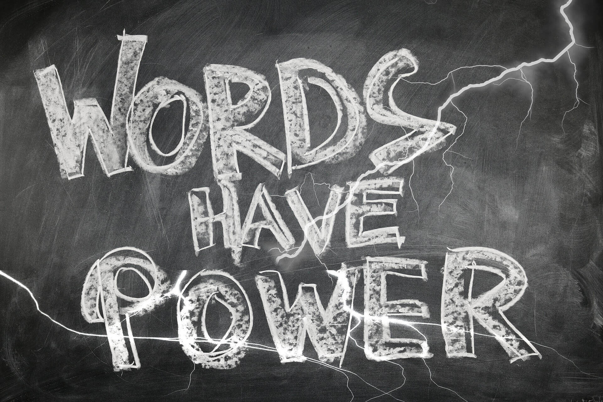 "Words have power" written in white chalk and in all caps appears on a blackboard.