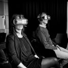 Two people sit wearing VR headsets.