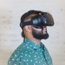 A bearded man with a green shirt wears a VR headset.