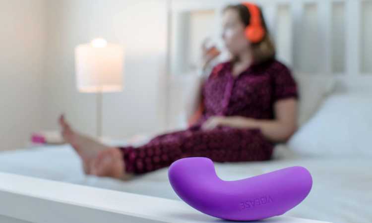 Woman lies on a  bed wearing headphones behind a purple Vibeae panty vibe.