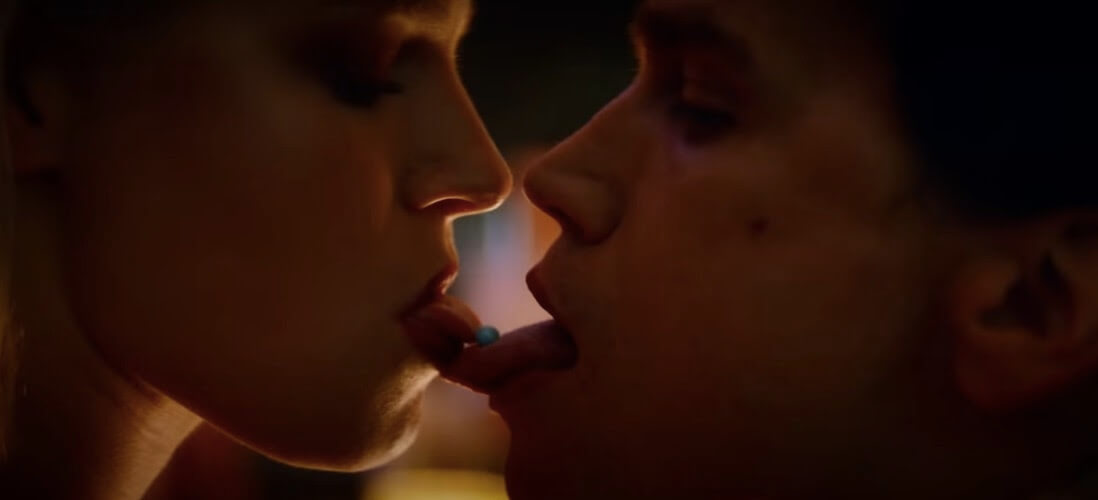 Two young people exchange a pill using their tongues as they appear to kiss. 