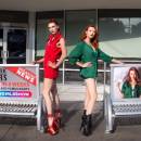 Two young women stand in platform heels posting next to bus benches showing ads for out of work strippers.