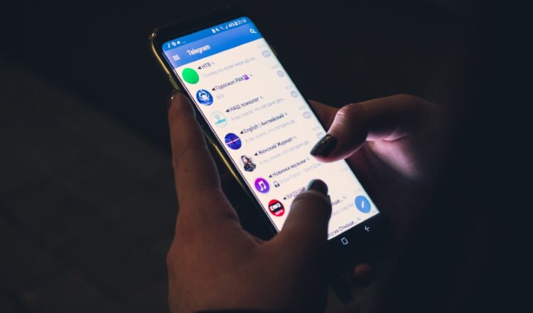 Closeup of a Telegram user scrolling the app on a smartphone.