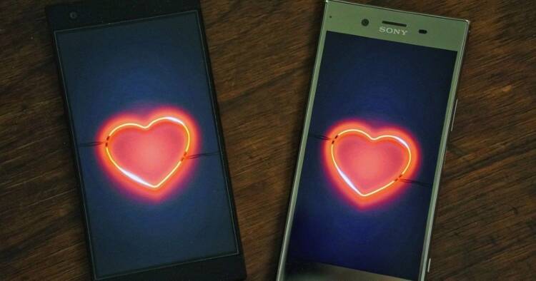 Two smartphones appear next to each other showing red hearts on their screens.