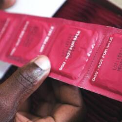 A man's hand shown holding a line of condoms.