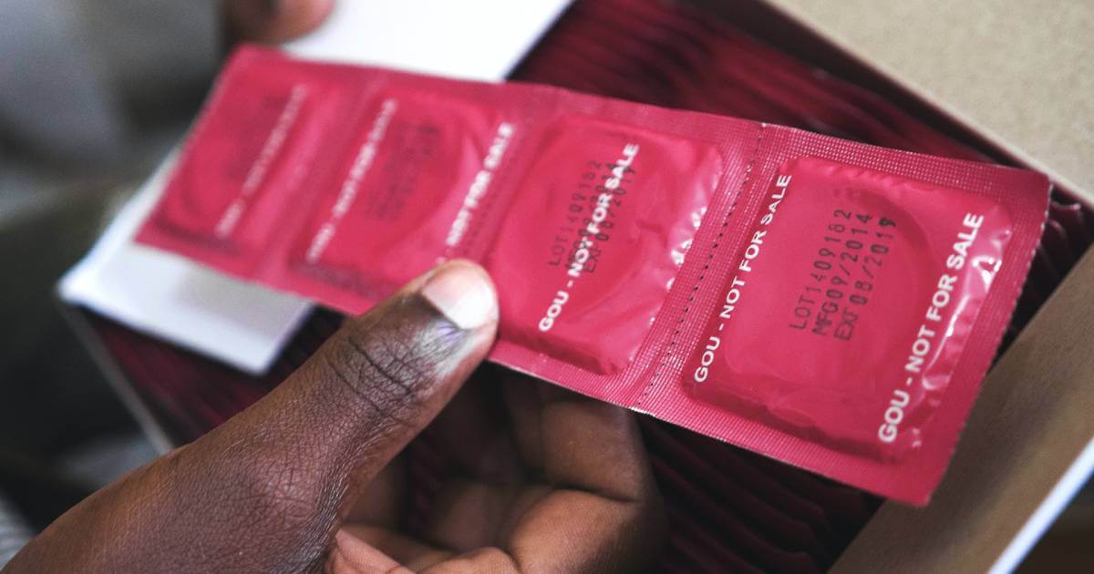 A man's hand shown holding a line of condoms.