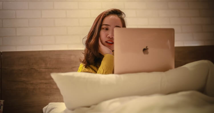 Picture of a girl working on her laptop in her bed