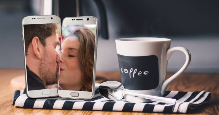 Picture of a couple kissing on phone with a coffee cup and steel spoon placed on napkin