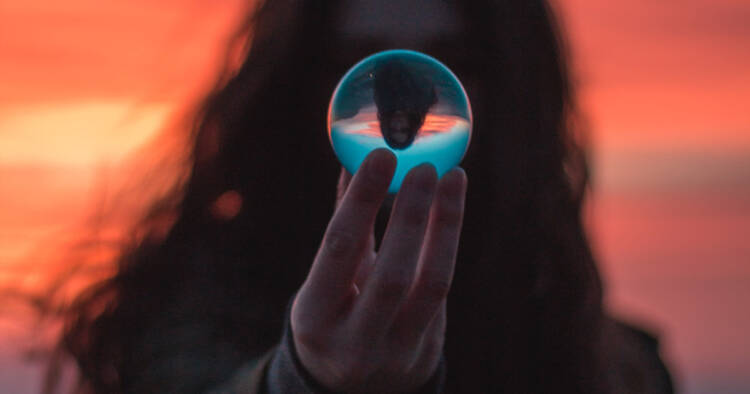 The silhouette of a person with long hair holding a crystal ball.