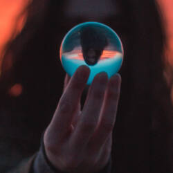 The silhouette of a person with long hair holding a crystal ball.