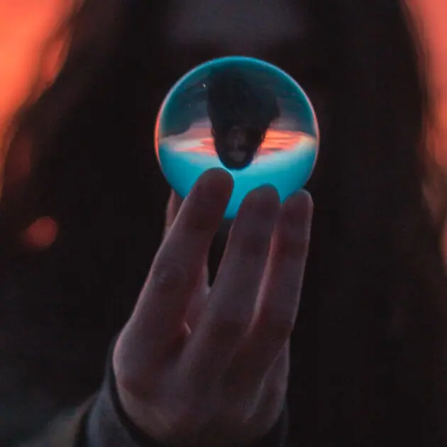 The silhouette of a person with long hair holding a crystal ball.