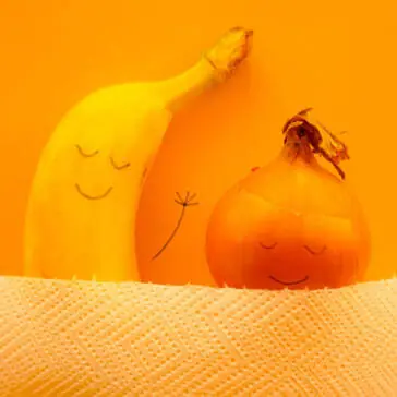 banana and onion sleeping in bed with faces drawn on them
