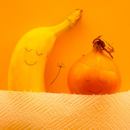 banana and onion sleeping in bed with faces drawn on them