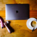 Sex toys sit next to a closed laptop and coffee on a wooden tabletop.
