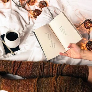 Image of female hands holding a book and coffee mug beside her