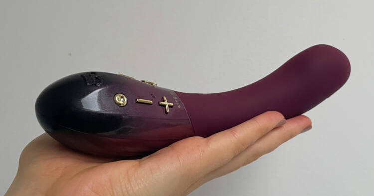 Hot Octopuss Kurve dual motor vibrator held in a white person's hand.