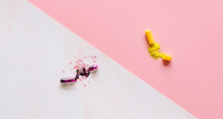 Decorative image of two pills with sparkles exploding out against a white and pink background.