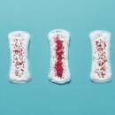 Five menstrual pads with varying degrees of red sprinkles on top to represent the various stages of periods.