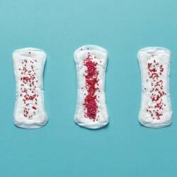 Five menstrual pads with varying degrees of red sprinkles on top to represent the various stages of periods.