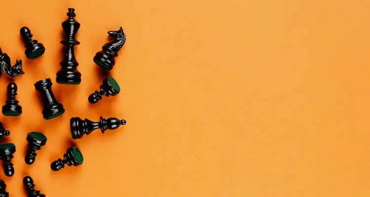 Black chess pieces laying across an orange background.