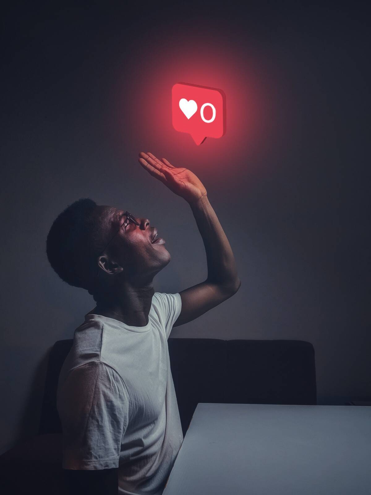 A decorative image of a man sitting at a table. He is looking up and holding out his hand. Above him is a glowing generic social media "like" count showing "0".