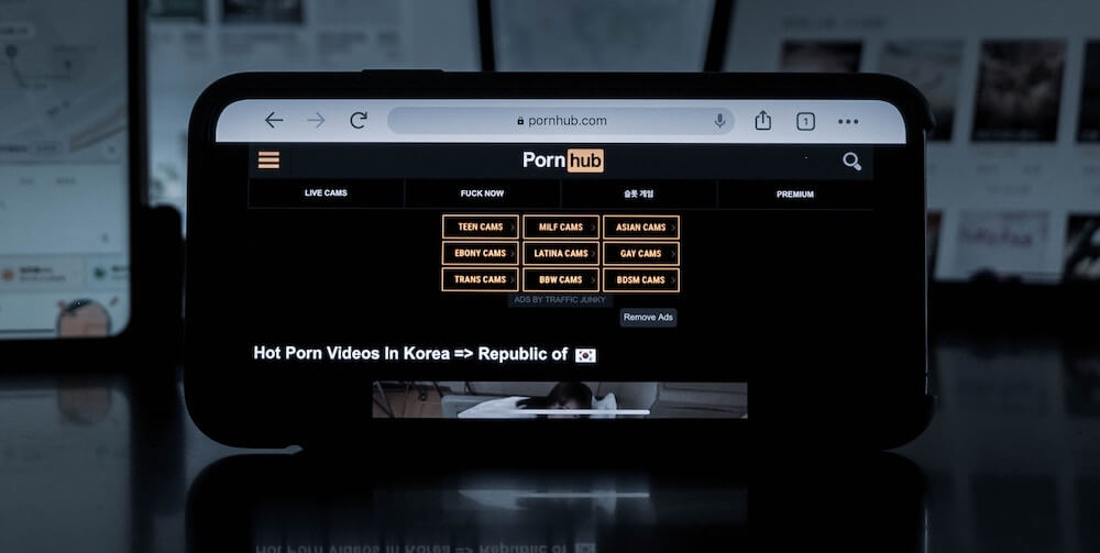 A laptop showing a page from the Pornhub website. The options listed include: Teen Cams, MILF Cams, Asian Cams, and more. 
